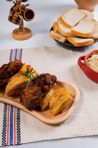 A vertical shot of fried meat and potatoes on the table with boiled rice, bread, and decorations