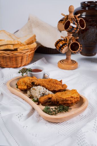 A vertical shot of fried crispy chicken with rice, greens, ketchup served with white bread