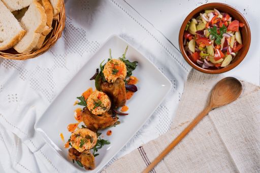 A top view of fresh salad, bread in a woven basket with fried chicken and rice with vegetables
