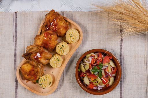A top view of fried chicken with sauce and dumplings served with a healthy vegetable salad