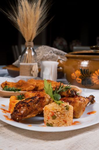 A selective focus shot of fried chicken and rice with vegetables served on a white plate