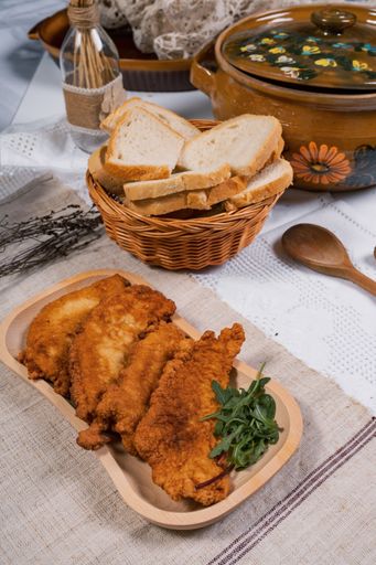 A vertical shot of fried crispy chicken with greens served with white bread