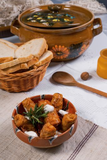 A vertical shot of cabbage dolma with a white sauce in a bowl served with white bread