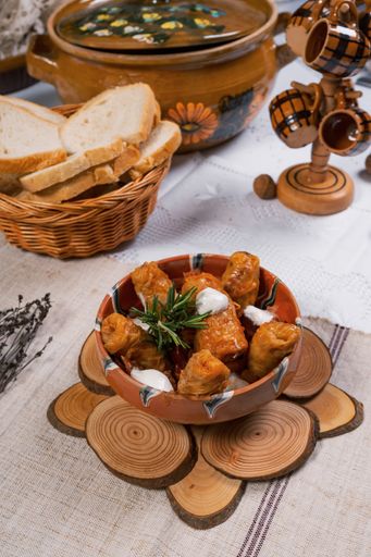 A vertical shot of cabbage dolma with a white sauce in a bowl served with white bread