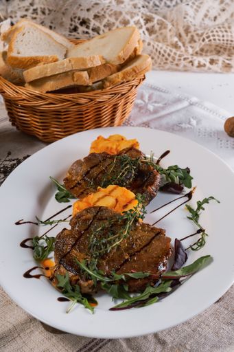 A vertical sho of delicious steaks with potatoes, greens, and a sauce, served with white bread