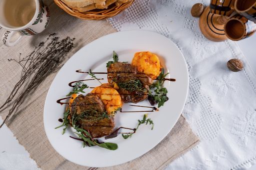 A top view of delicious steaks with potatoes, greens, and a sauce