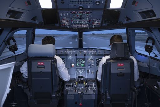 the two pilots in the cockpit of a commercial flight simulator preparing to start the flight