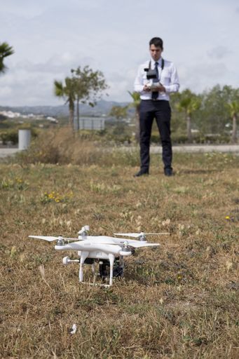 a vertical shot of a caucasian drone pilot from Spain piloting during a drone flight practice in a field with trees