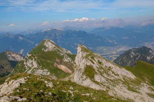A beautiful landscape of a mountain range with a lush grassy valley at its base