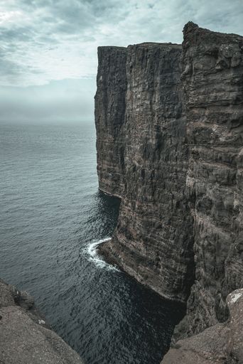 A vertical shot of majestic rocky cliffs on the  Faroe Islands on a gloomy day