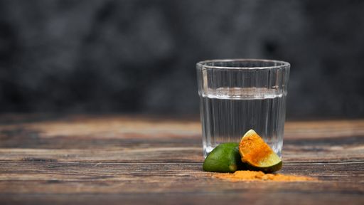 A closeup shot of a tequila shot with spicy pepper slices
