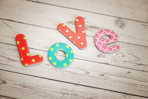 A closeup shot of colorful cardboard letters spelling out "love" on a wooden surface