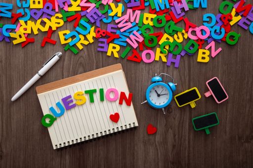 A top view of colorful letters spelling "question" on a wooden table