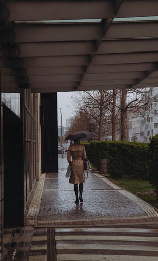 A person walking along a city street on a rainy day with an open umbrella