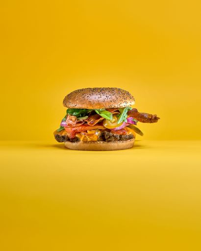 An appealing hamburger stacked on a bright yellow background
