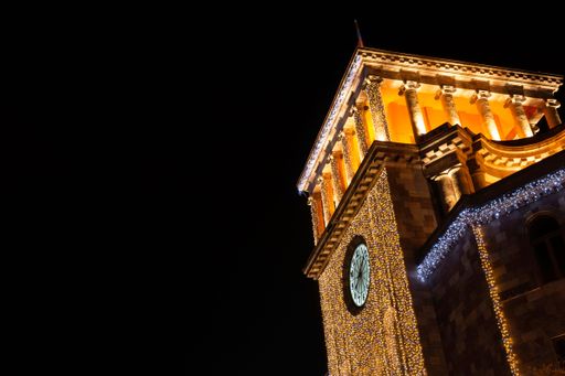 A stunning night view of the illuminated clock tower located in the Republic Square of Armenia
