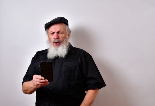 A senior man looking at this smartphone with a serious face expression