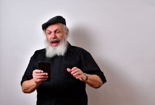 A senior man looking at this smartphone with a serious face expression