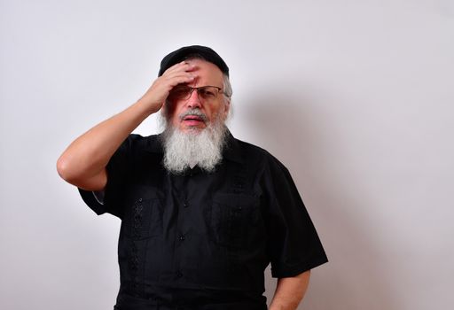 A distressed senior man holding his forehead in despair