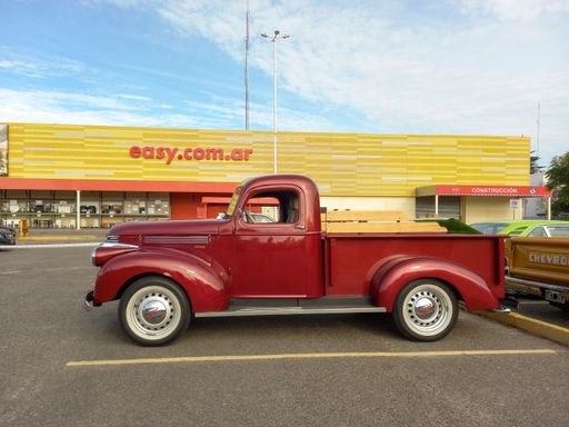 Side view of an old red 1946 Chevrolet Chevy AK series 250 pickup truck in a parking lot at a classic car show.