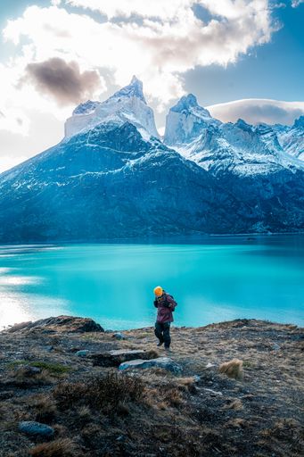 An adult hiker looking at rocky snowy mountains in Torres del Paine National Park, Chile