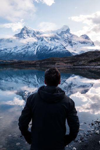An adult hiker looking at rocky snowy mountains in Torres del Paine National Park, Chile