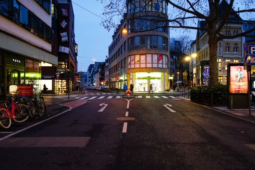 empty street in city of cologne with illuminated shops at dawn