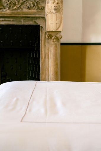 A bed in a cozy bedroom with a stone fireplace in the background