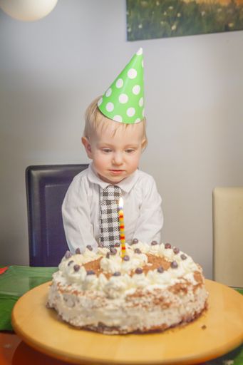 A vertical shot of a toddler boy with his birthday cake