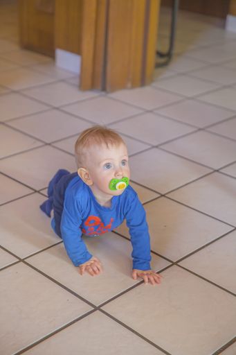 A vertical shot of a toddler on a floor