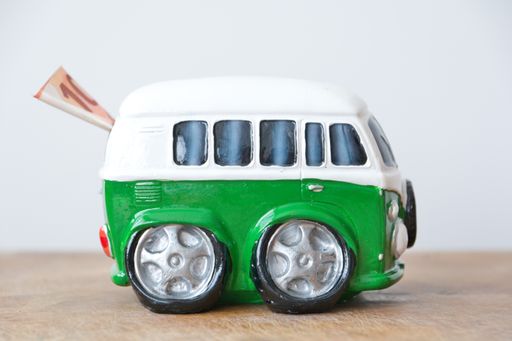 Antwerp, Belgium, April 2021: Side view of a miniature retro van used as piggy bank or money box with 10 euro bill