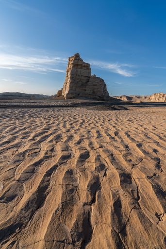 An expansive rock formation set against a backdrop of barren desert terrain. Gobi Desert, China.