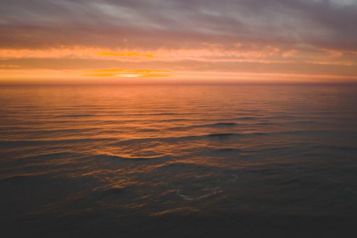 The mesmerizing view of the calm ocean under the colorful sky during sunset