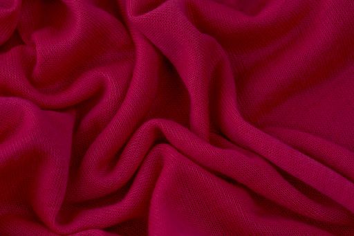 A pink toned blanket with large and deep pleats and a textured fabric backing