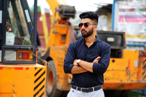 An Indian businessman in a black shirt with a tractor on the background