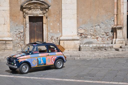 colorful old car in front of a church facade in Taormina, Sicily, Italy