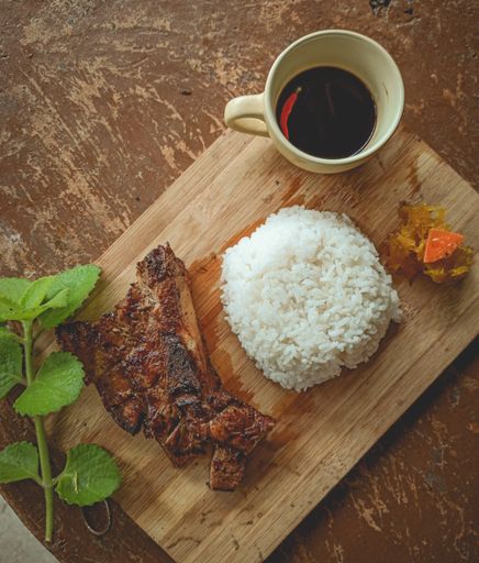 A top view of delicious meat with rice and a cup of coffee on a wooden board