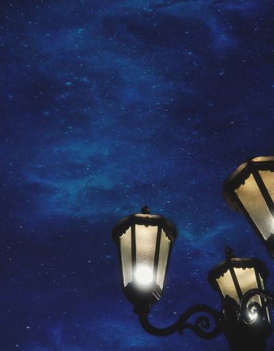 A closeup of illuminated street light against the night sky