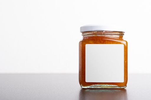 A juicy homemade carrot jam in a glass jar on a white background, editable mock-up series template ready for your design