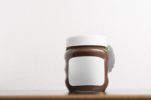 A hazelnut spread chocolate jar with a round cap on black table, editable mock-up series template ready for your design, selection path included.