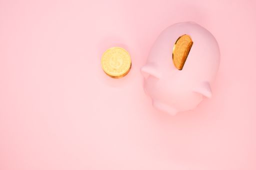 An overhead shot of a piggy bank and coins on a pink background with space for your text - savings and banking concept