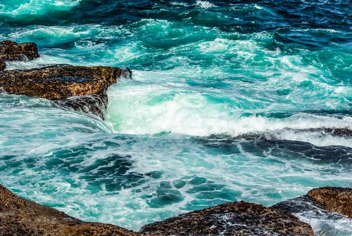 A beautiful view of splashing sea waves and rock formations under the sunlight