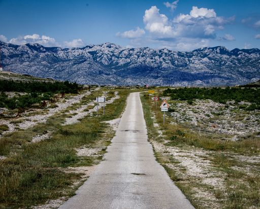 A beautiful view of a road surrounded by rocky mountains under a cloudy sky