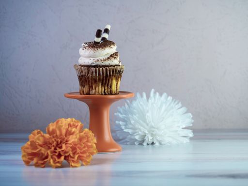 A closeup of buttercream flavored cupcake with flowers on the table