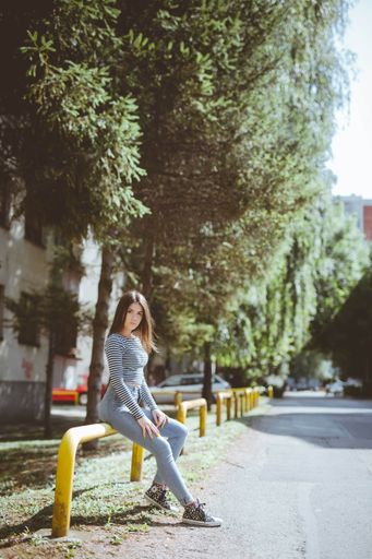 Vertical shot of a beautiful Caucasian woman wearing a striped shirt and jeans posing outdoors