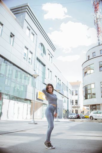 A full body shot of a Bosnian brunette girl in cool summer outfit posing in the street on a sunny day