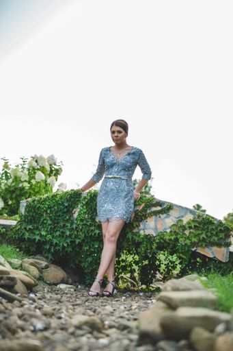 A vertical shot of an attractive female wearing a nice dress posing in a beautiful garden