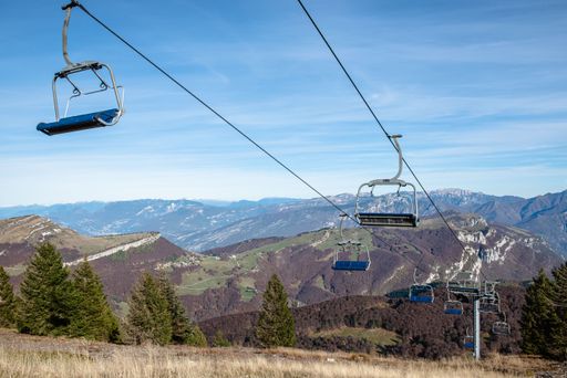 The empty ski lift above a rocky hillside landscape with rocky peaks in the distance