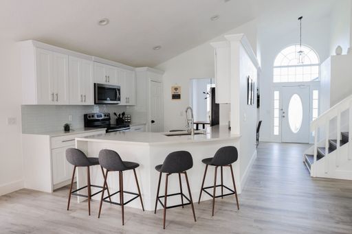 A modern kitchen featuring an open floor plan with a center island, surrounded by contemporary bar stools providing additional seating