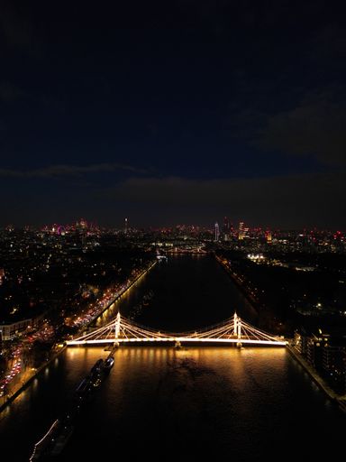 A stunning aerial view of Albert Bridge in London, illuminated by a myriad of vibrant lights